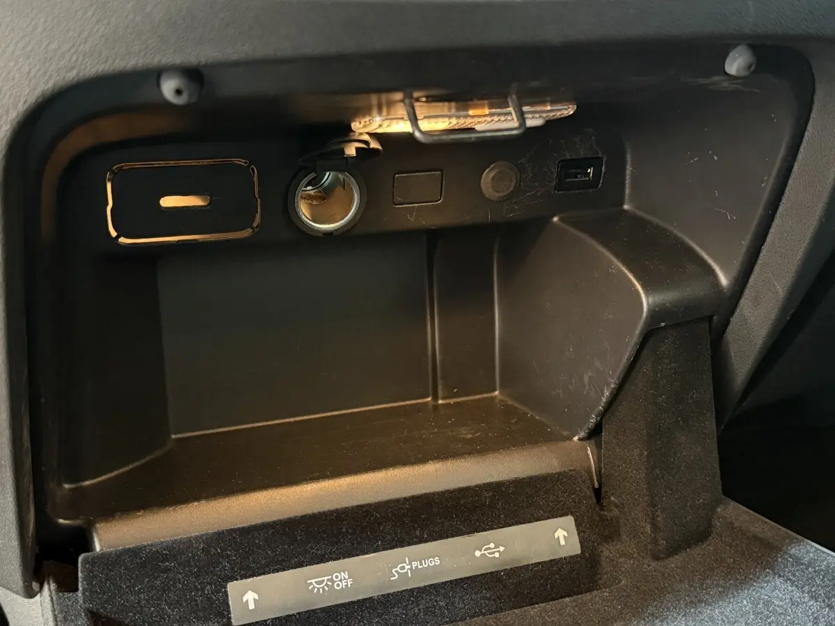 Gros plan sur la boîte à gants noire du Citroën Grand C4 Spacetourer avec prise 12V et port USB visibles.