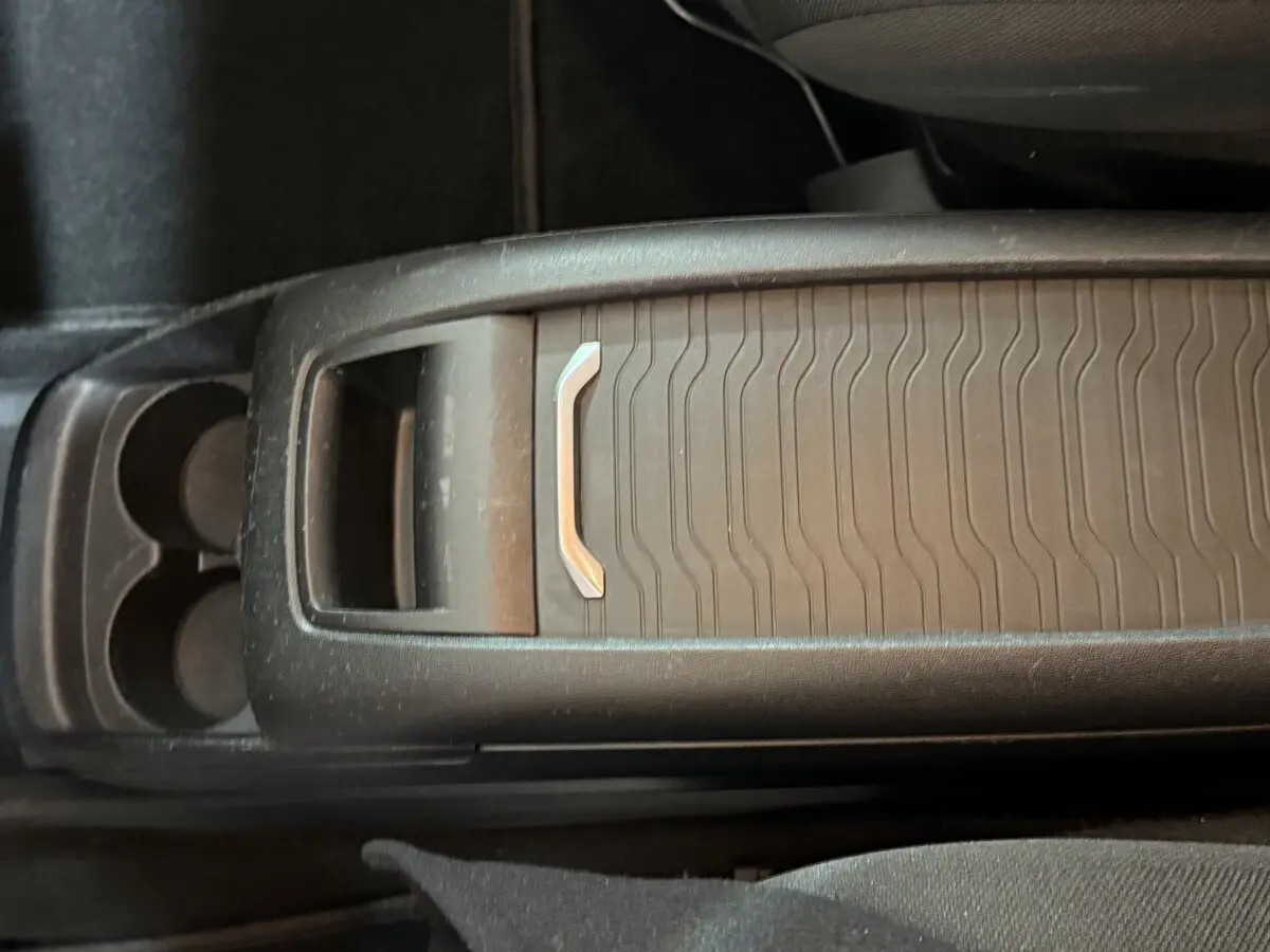 Gros plan sur la console centrale noire du Citroën Grand C4 Spacetourer avec porte-gobelets et rangement coulissant.