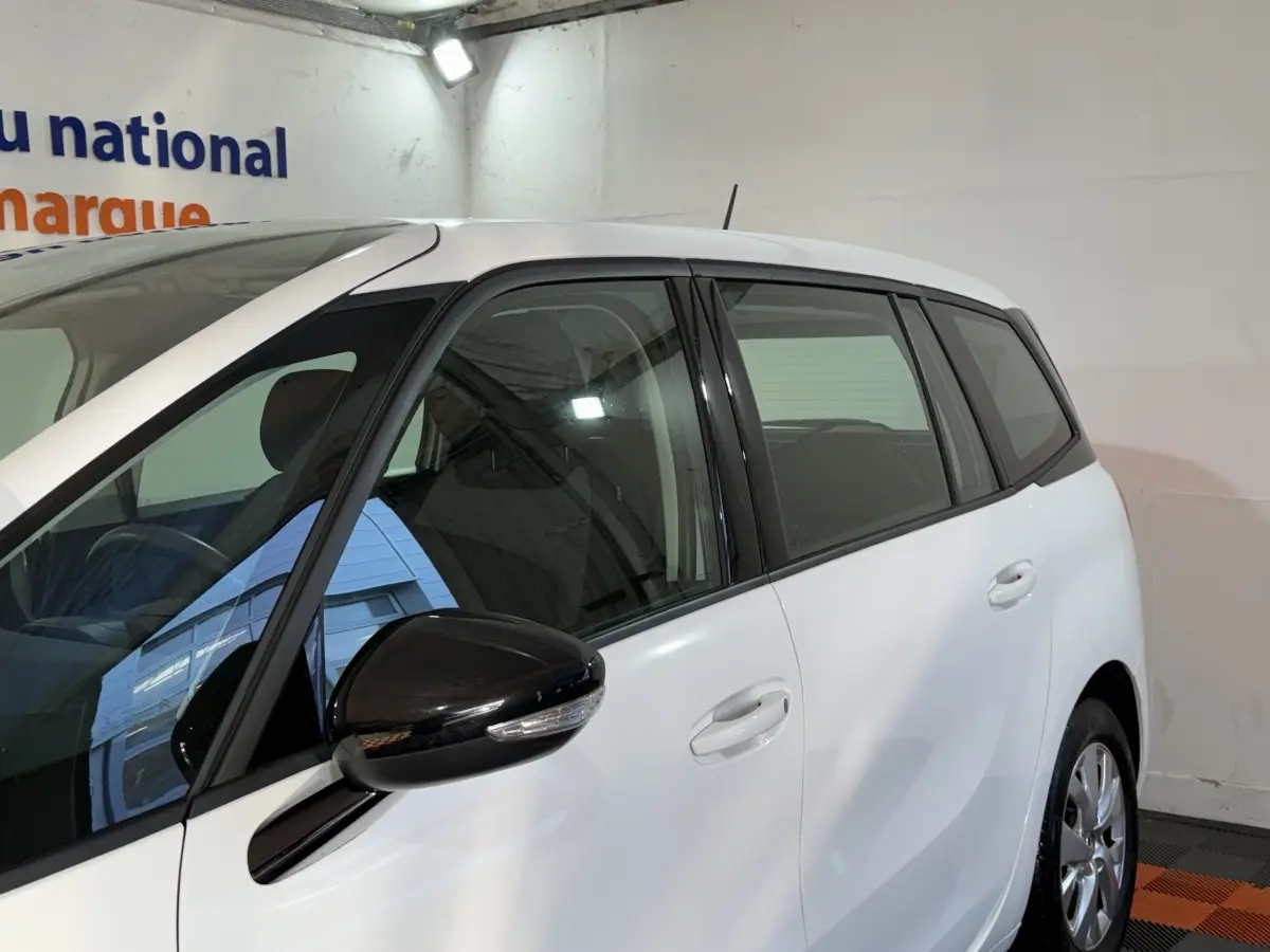 Vue côté gauche avant d'un Citroën Grand C4 Spacetourer blanc avec rétroviseur noir et vitres teintées.