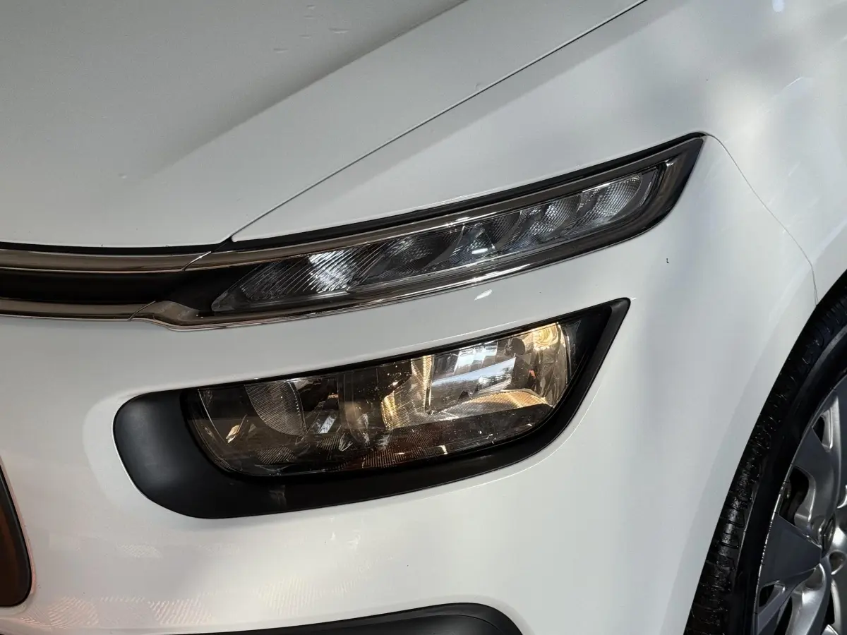 Gros plan sur le phare avant droit blanc du Citroën Grand C4 Spacetourer 2021 avec détails du feu et partie de la roue.