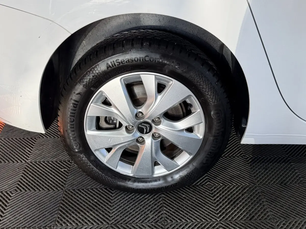 Gros plan sur la roue arrière droite blanche d'un Citroën Grand C4 Spacetourer avec jante argentée et logo Citroën.