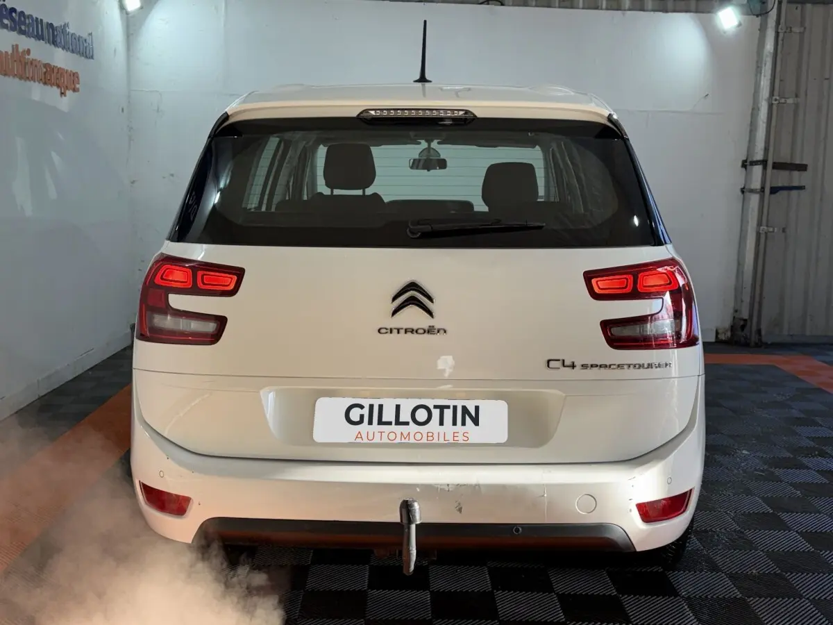 Vue arrière d'un Citroën Grand C4 Spacetourer blanc avec feux allumés et attelage visible en intérieur.