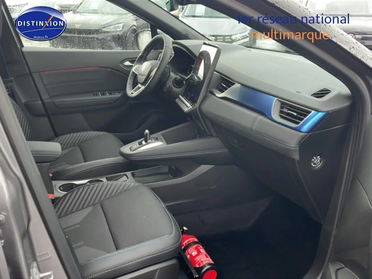 Intérieur avant droit du Renault Captur gris cassiopée avec tableau de bord noir et inserts bleus esprit Alpine.