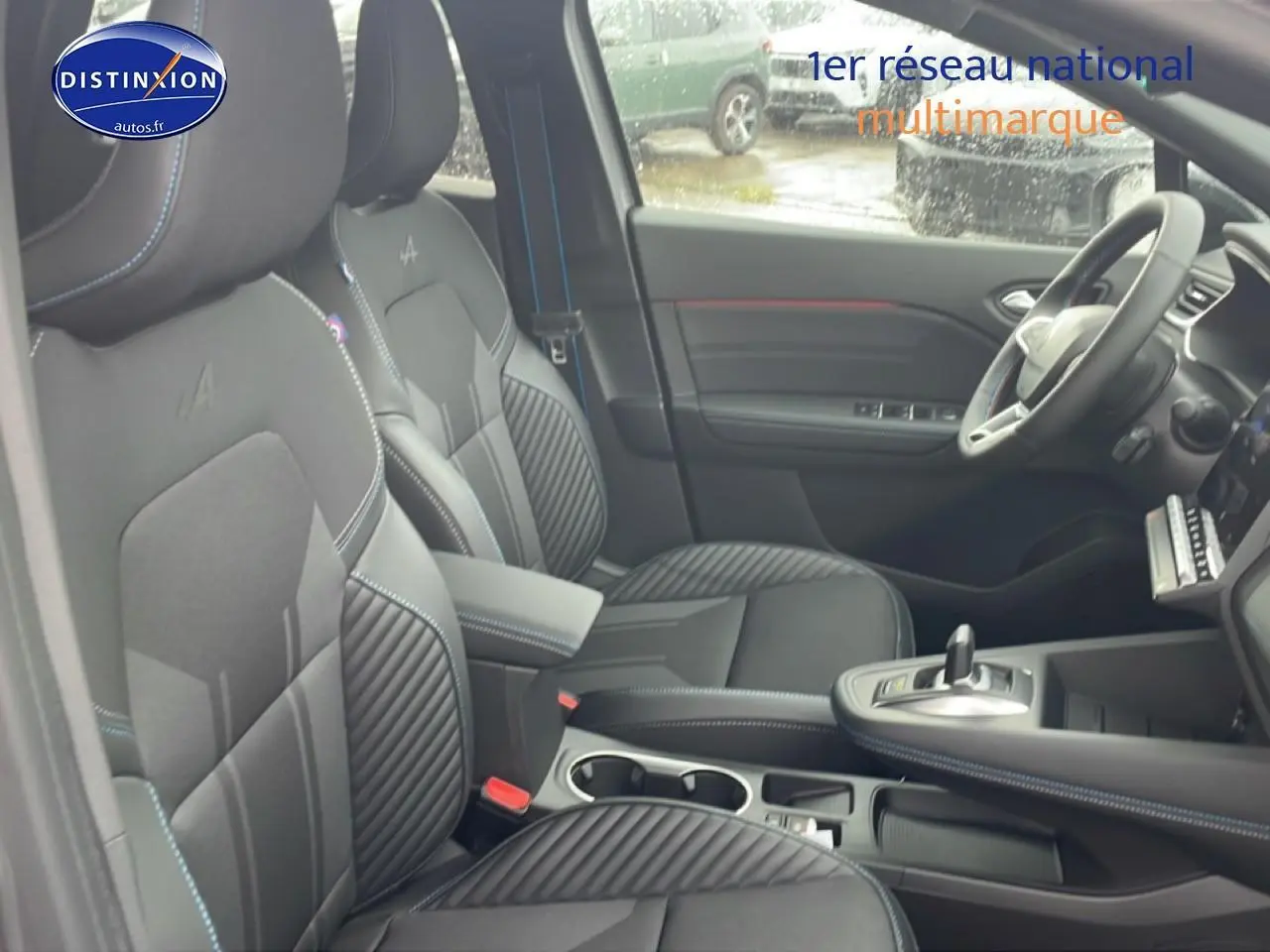 Vue intérieure côté conducteur du Renault Captur 1.8 e-tech hybride, sièges noirs esprit Alpine avec surpiqûres bleues.
