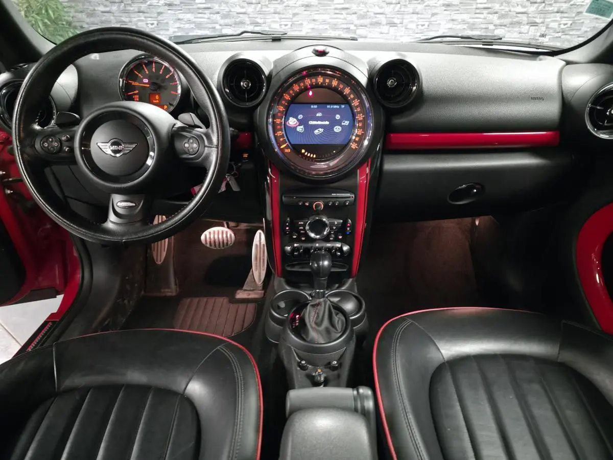 Vue intérieure avant du MINI Countryman John Cooper Works 2015, tableau de bord et console centrale avec touches rouges sportives.