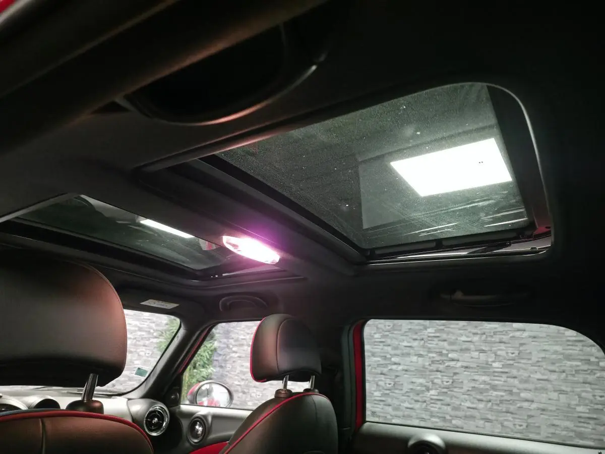 Vue intérieure du toit ouvrant en verre du MINI Countryman John Cooper Works rouge, avec sièges avant en cuir noir.