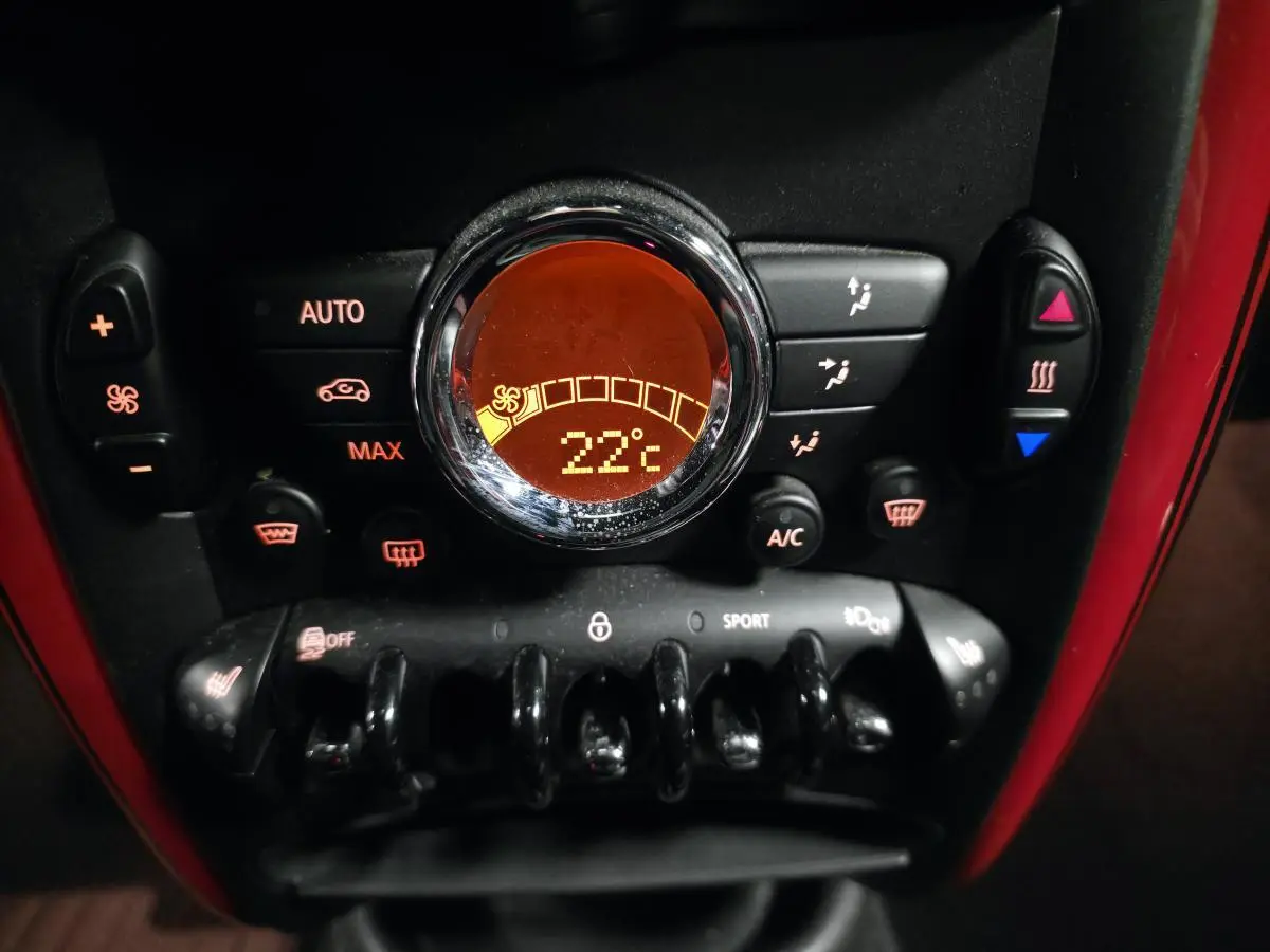 Gros plan sur la console centrale rouge du MINI John Cooper Works avec affichage digital de la climatisation à 22°C.