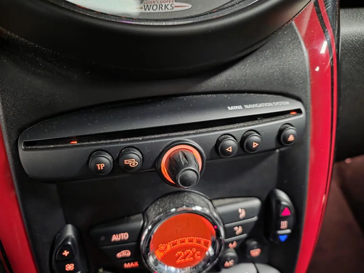 Gros plan sur la console centrale rouge et noire du MINI John Cooper Works avec commandes de climatisation et navigation.