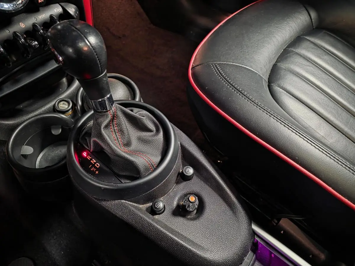 Gros plan sur levier de vitesses et siège avant droit en cuir noir avec surpiqûres rouges dans MINI Countryman John Cooper Works rouge.