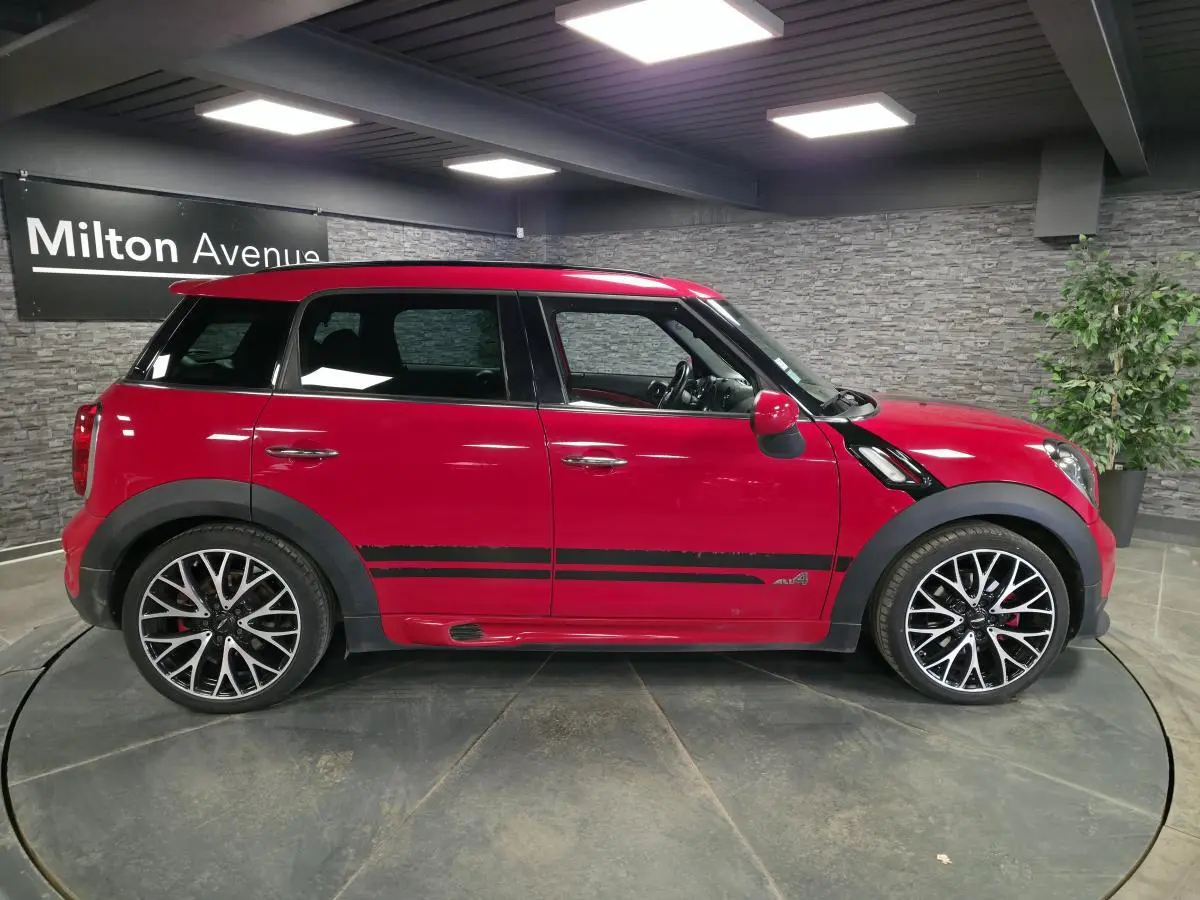 Profil droit d'un MINI Countryman John Cooper Works rouge avec bandes noires sport et jantes alliage noires et argent.