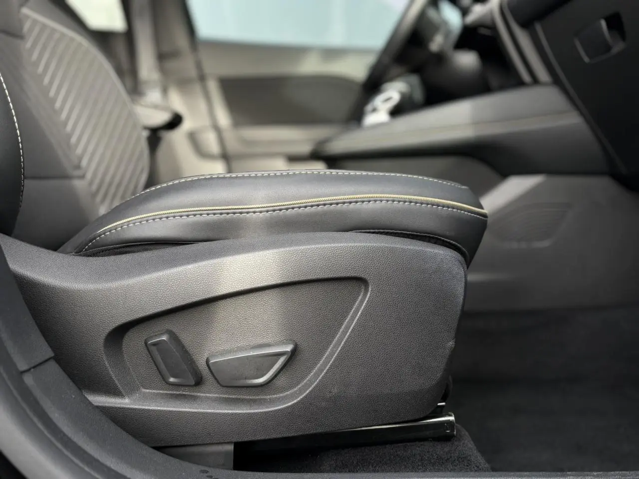 Détail du siège conducteur noir avec réglages électriques et surpiqûres contrastantes dans l’habitacle Renault Symbioz.