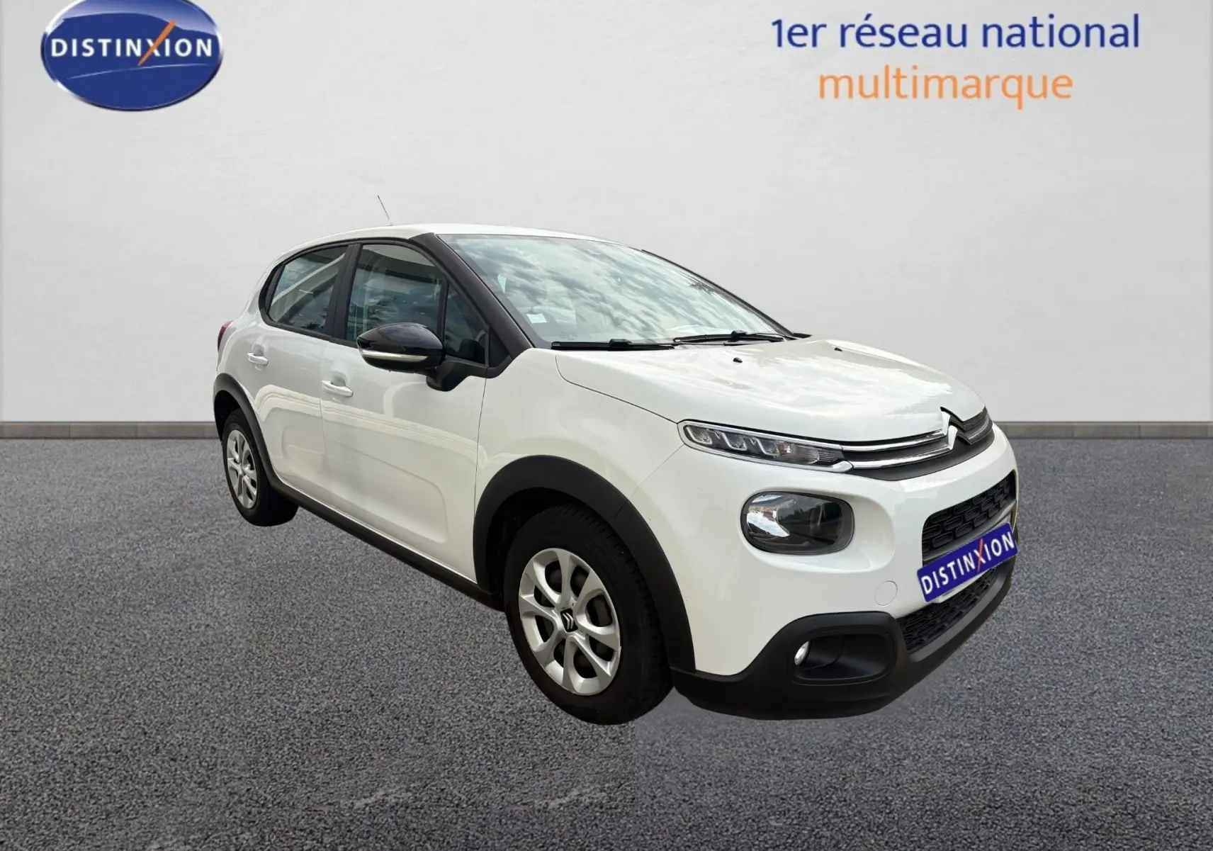 Citroën C3 blanc vue 3/4 avant droit, avec détails noirs contrastants sur les rétroviseurs et protections basses.