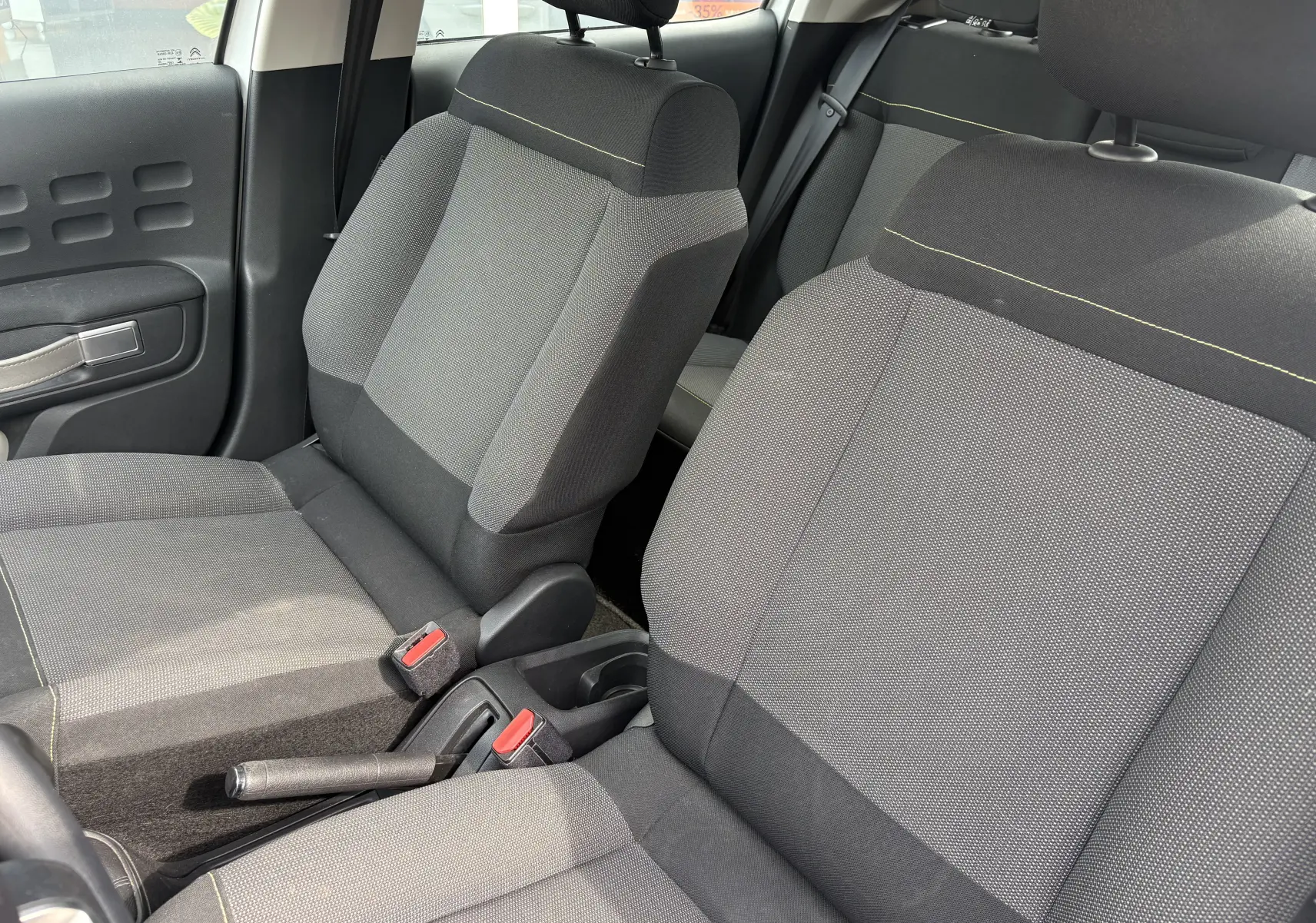 Vue intérieure rapprochée des sièges avant gris foncé et clair du Citroën C3 2019, avec détails de couture jaune.