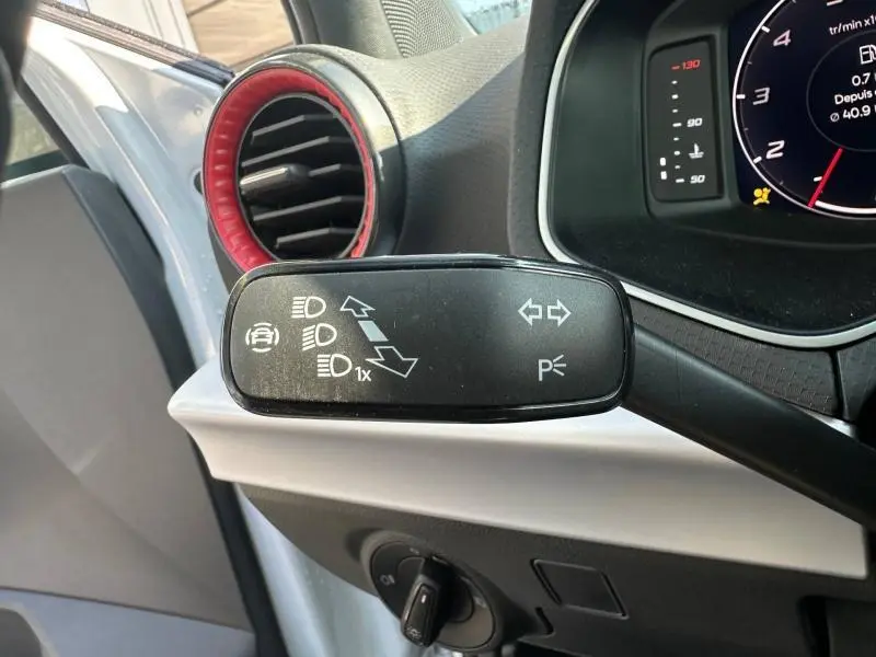 Gros plan sur la manette de clignotants à gauche du volant dans l’habitacle du SEAT Arona blanc avec cerclage d’aération rouge.