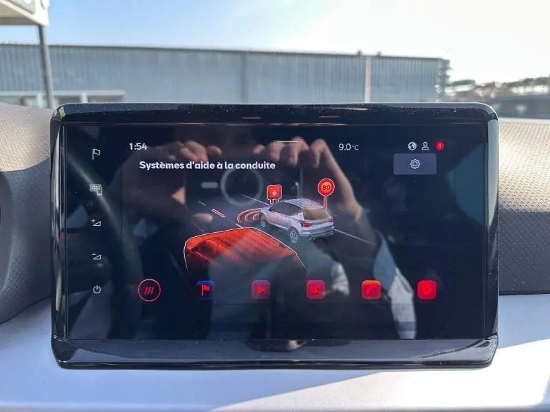 Écran tactile du système d’aide à la conduite dans un SEAT Arona 2025, affichage moderne avec icônes rouges.