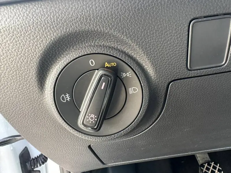 Gros plan sur le sélecteur de phares noir dans l’habitacle du SEAT Arona 2025, avec surface texturée noire autour.