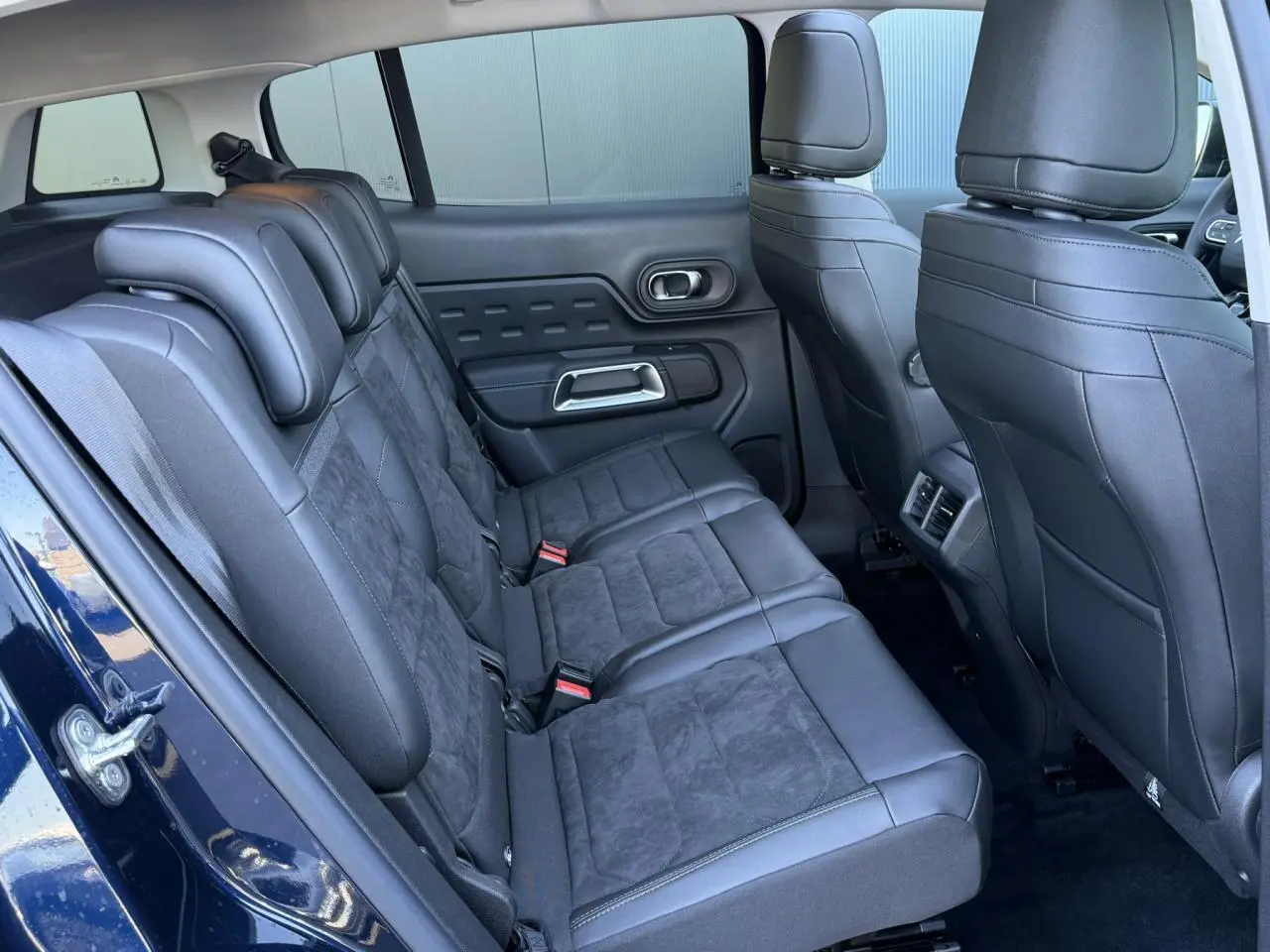 Vue intérieure arrière gauche des sièges en alcantara noir du Citroën C5 Aircross Bleu Eclipse avec portes ouvertes.
