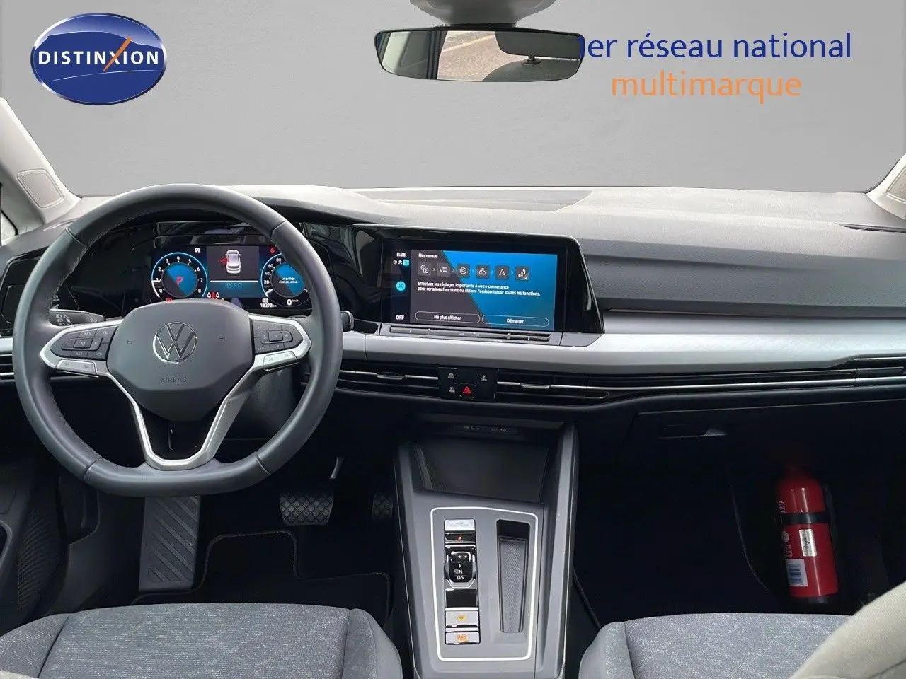 Vue intérieure avant du tableau de bord et volant d'une Volkswagen Golf VIII bleu lapiz metal avec écran tactile et commandes modernes.