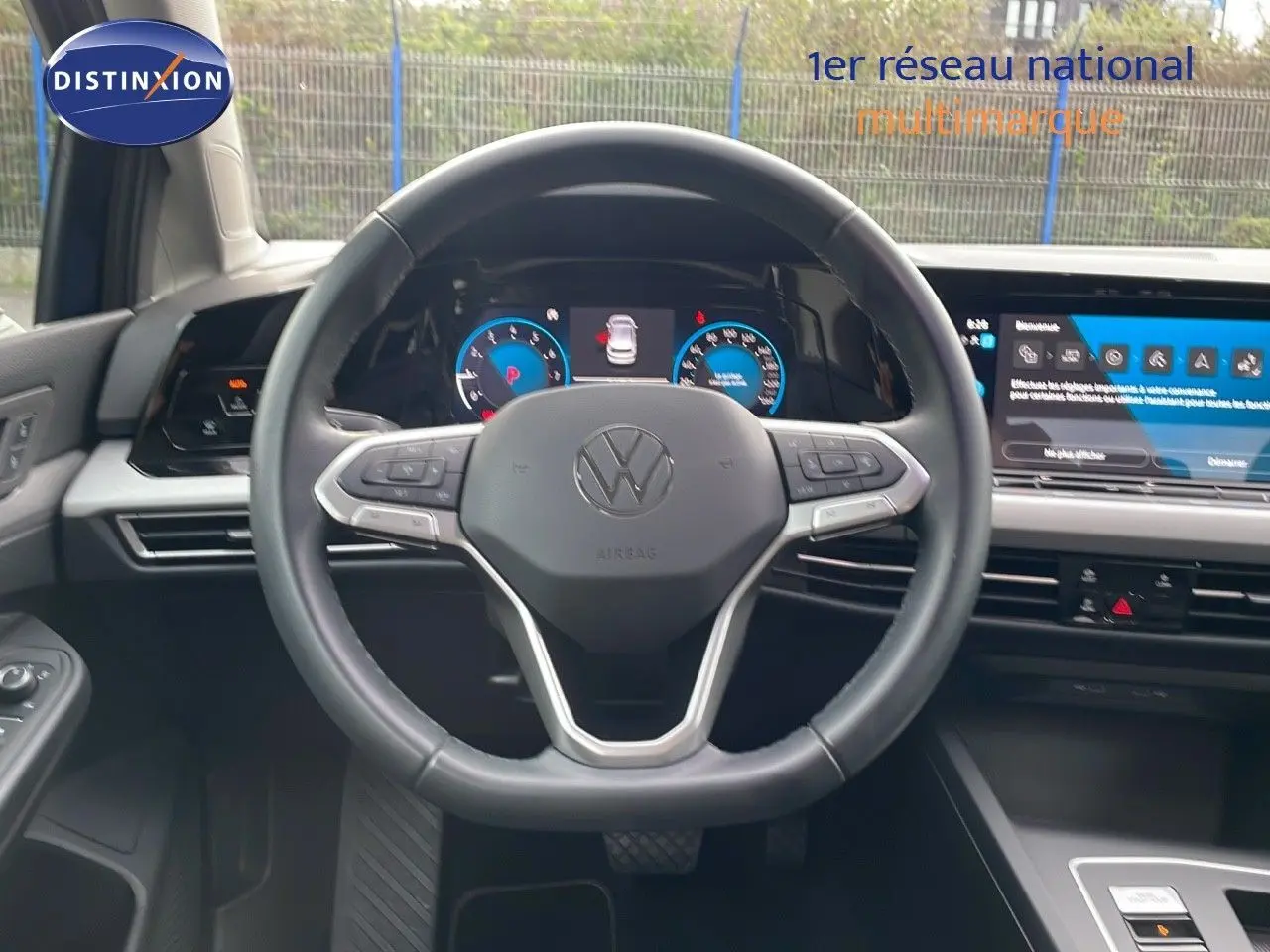 Volant cuir noir et tableau de bord digital d'une Volkswagen Golf VIII bleu lapiz metal, vue intérieure frontale.