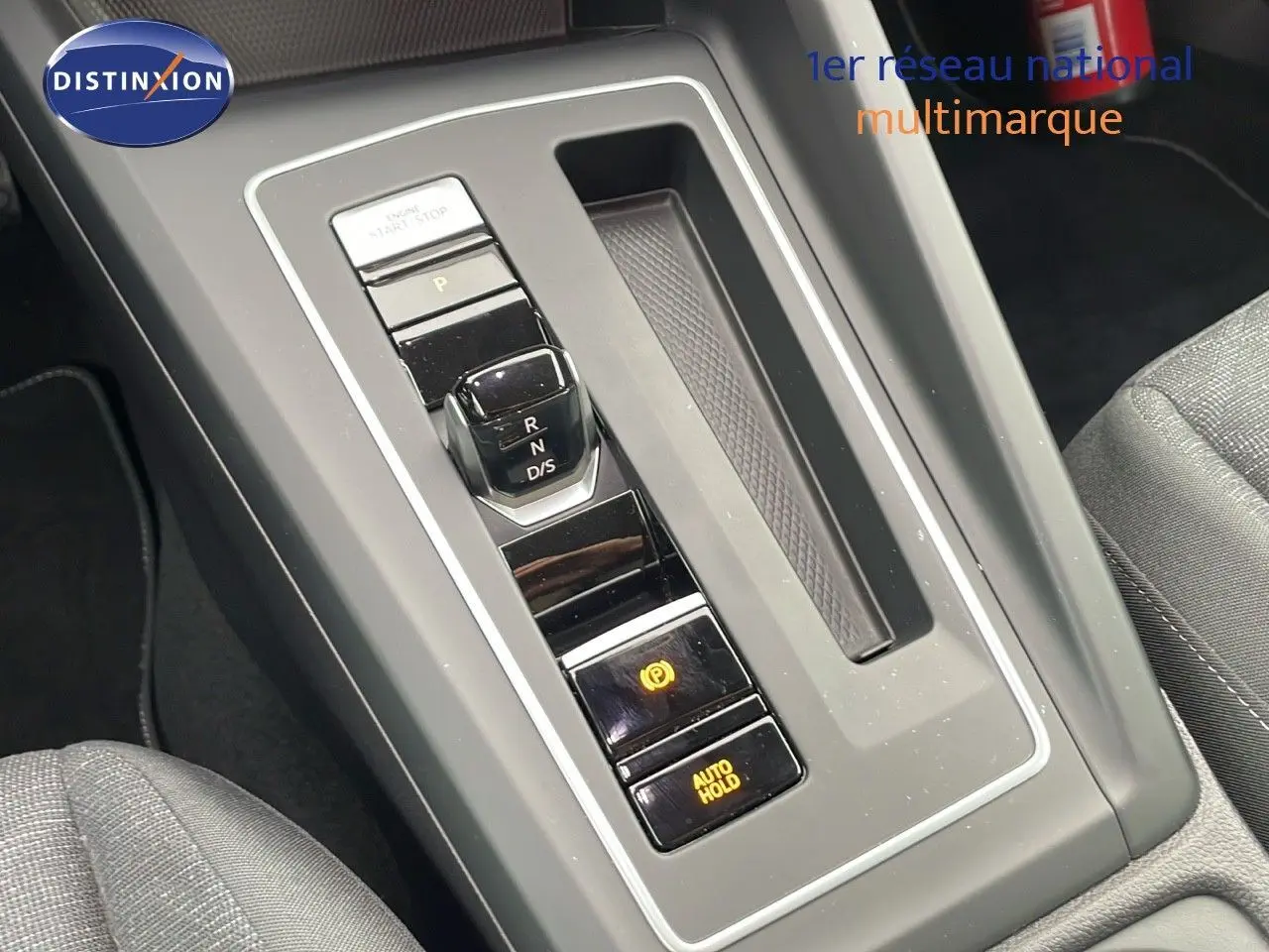 Gros plan sur la console centrale avec levier de vitesse automatique et boutons de frein à main et maintien auto sur Volkswagen Golf VIII.