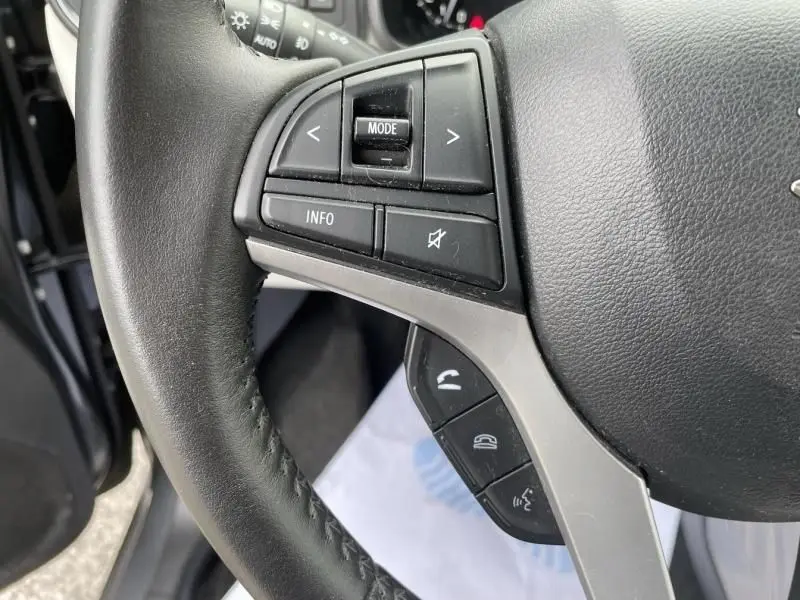 Gros plan sur le volant côté gauche du Suzuki Ignis gris foncé 2020, avec commandes multimédia et téléphone intégrées.