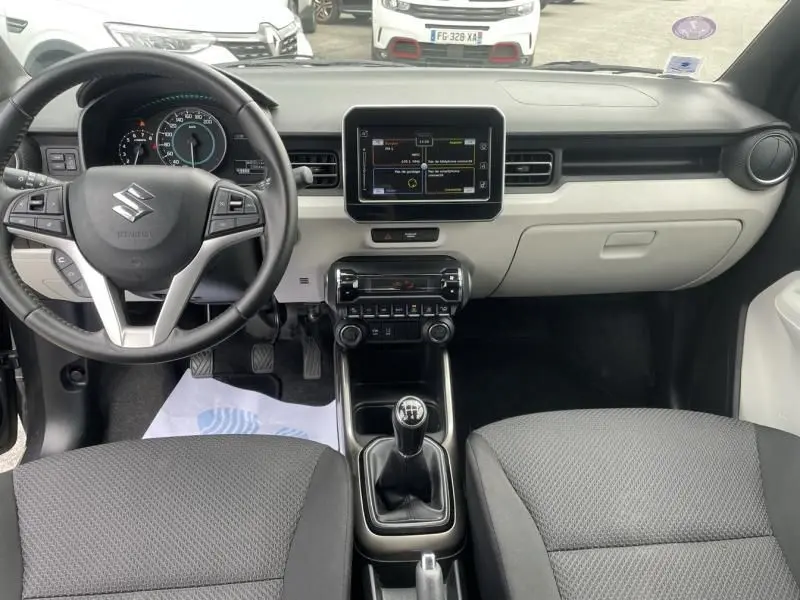 Vue intérieure avant du Suzuki Ignis 2020 gris foncé, avec tableau de bord moderne et boîte manuelle visible.