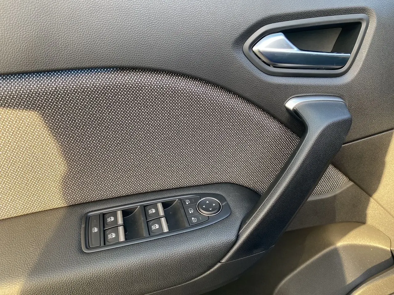 Gros plan sur la porte intérieure côté gauche du Renault Captur 2025, montrant les commandes de vitres et la poignée noire.