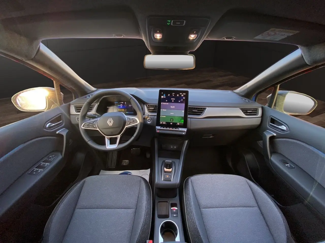 Vue intérieure avant du Renault Captur 2025, tableau de bord moderne avec écran tactile vertical et sièges gris foncé.