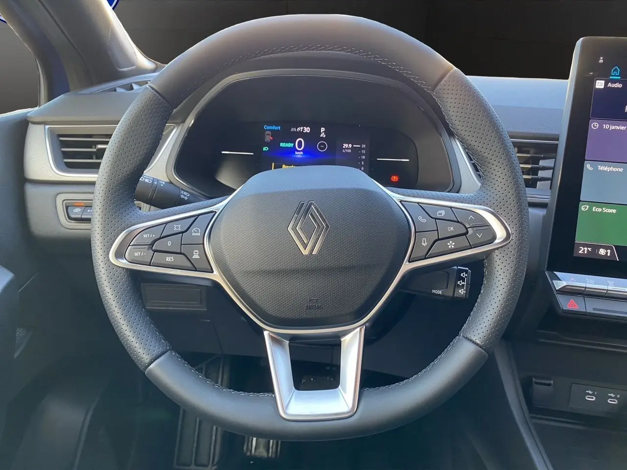 Vue rapprochée du volant noir perforé du Renault Captur 2025 avec tableau de bord numérique et écran tactile à droite.