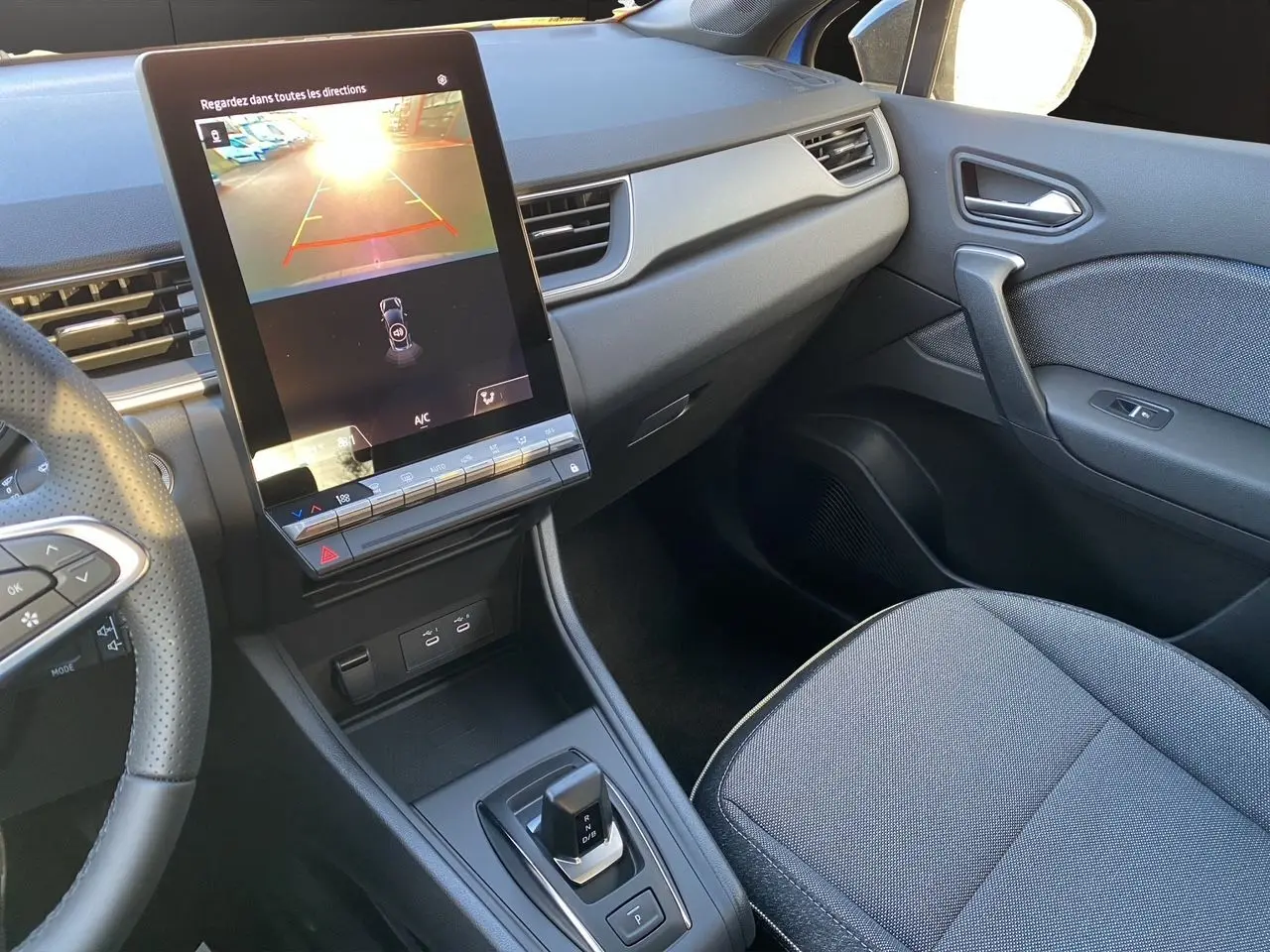 Vue intérieure du tableau de bord et console centrale du Renault Captur 2025 avec écran tactile et levier de boîte automatique.