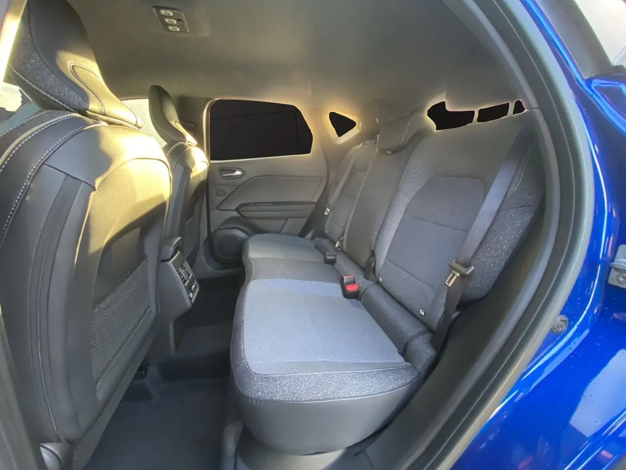 Vue intérieure arrière côté droit du Renault Captur 2025 bleu Iron avec sièges tissu et garnitures noires.