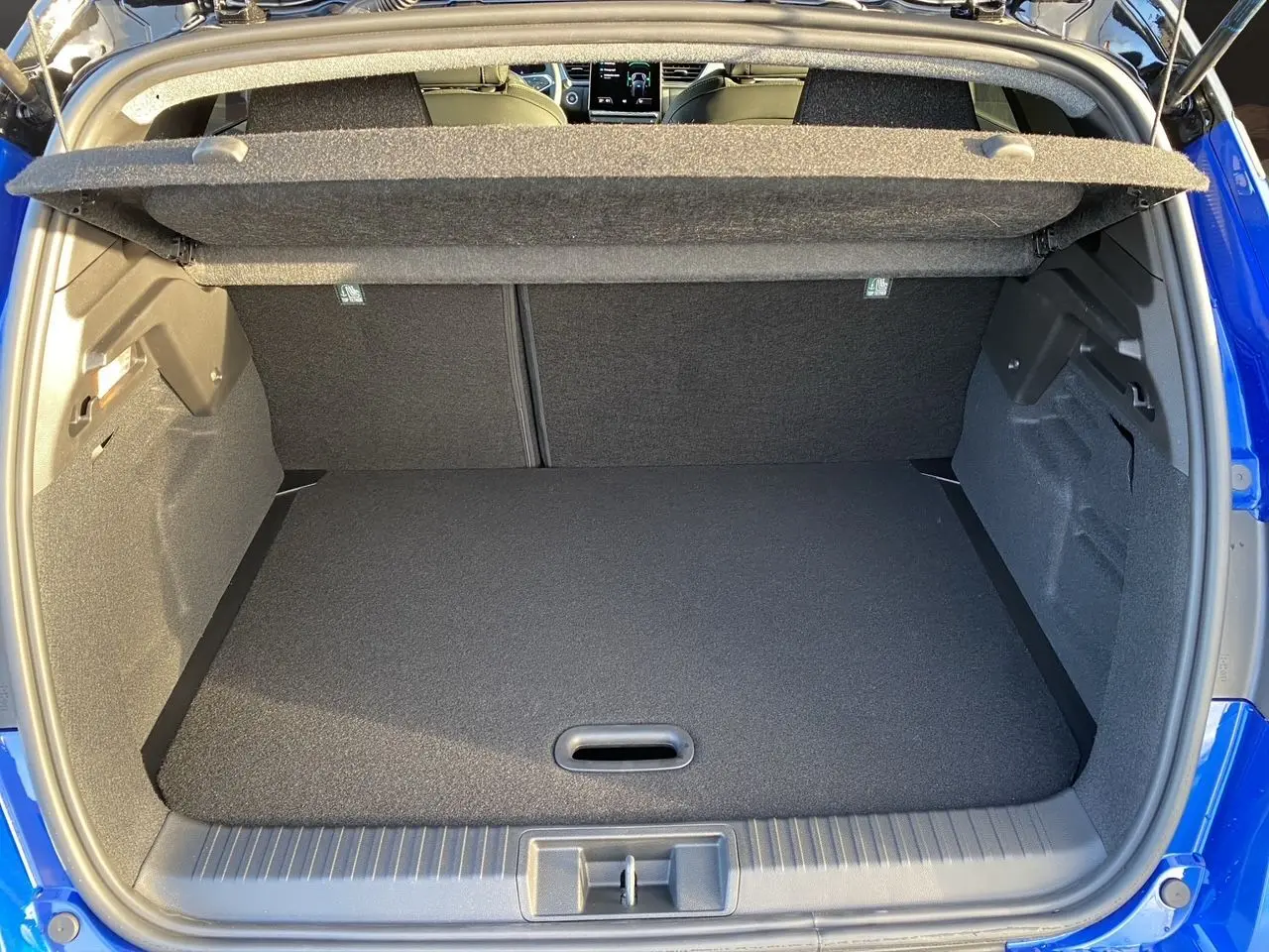 Coffre ouvert du Renault Captur bleu 2025, vue arrière montrant l’espace de rangement et la tablette cache-bagages.