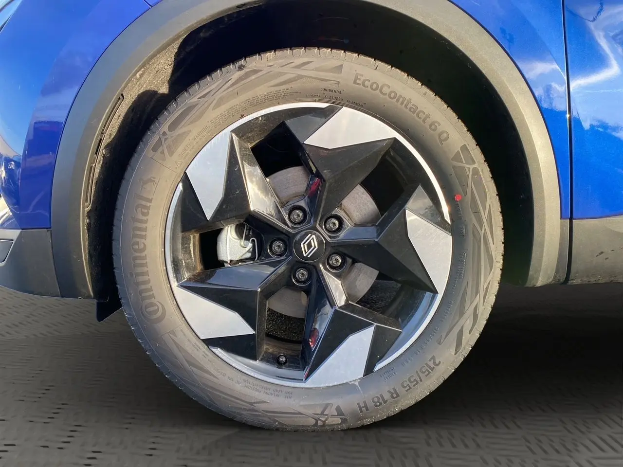 Gros plan sur la roue avant droite du Renault Captur bleu Iron 2025 avec jante noire et argentée au design géométrique.