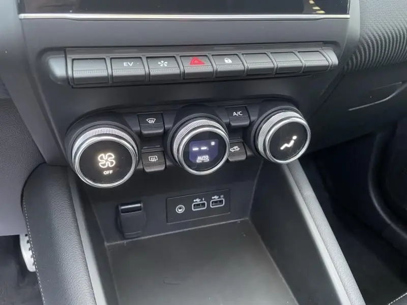 Gros plan sur la console centrale du Renault Captur blanc nacré 2023, montrant les commandes de climatisation et ports USB.