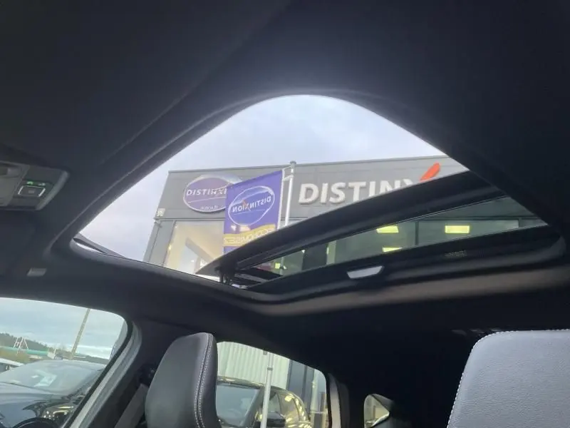 Vue intérieure du toit ouvrant panoramique du Renault Captur blanc nacré 2023, avec sièges en cuir visibles.