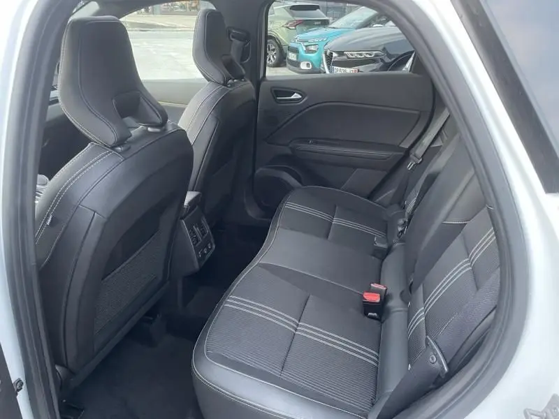 Vue intérieure côté droit sur les sièges arrière noirs avec surpiqûres blanches du Renault Captur blanc nacré 2023 hybride.