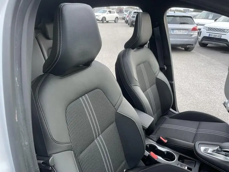 Vue intérieure du Renault Captur 1.6 E-Tech hybride 2023 montrant les sièges avant en cuir noir avec surpiqûres blanches.