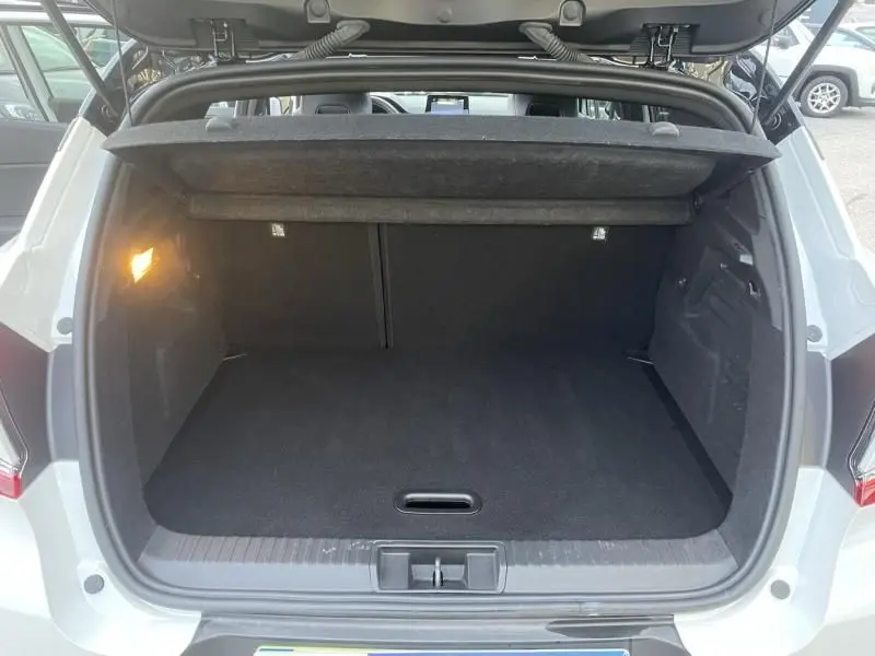 Coffre ouvert vu de l'arrière d'un Renault Captur blanc nacré 2023, montrant un espace de chargement vide et propre.