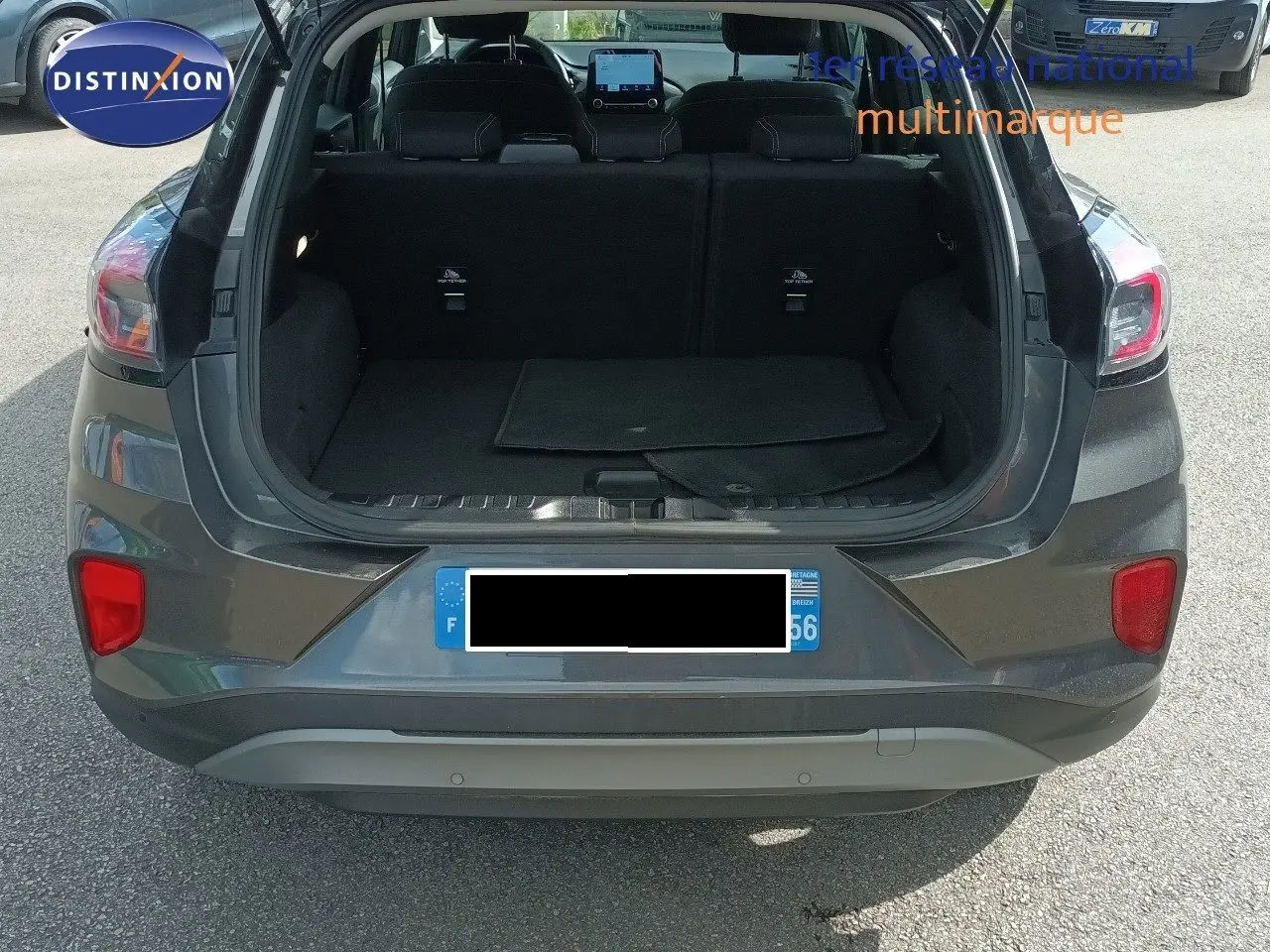 Vue arrière du Ford Puma gris foncé métal 2023 avec coffre ouvert montrant l’espace de chargement vide.