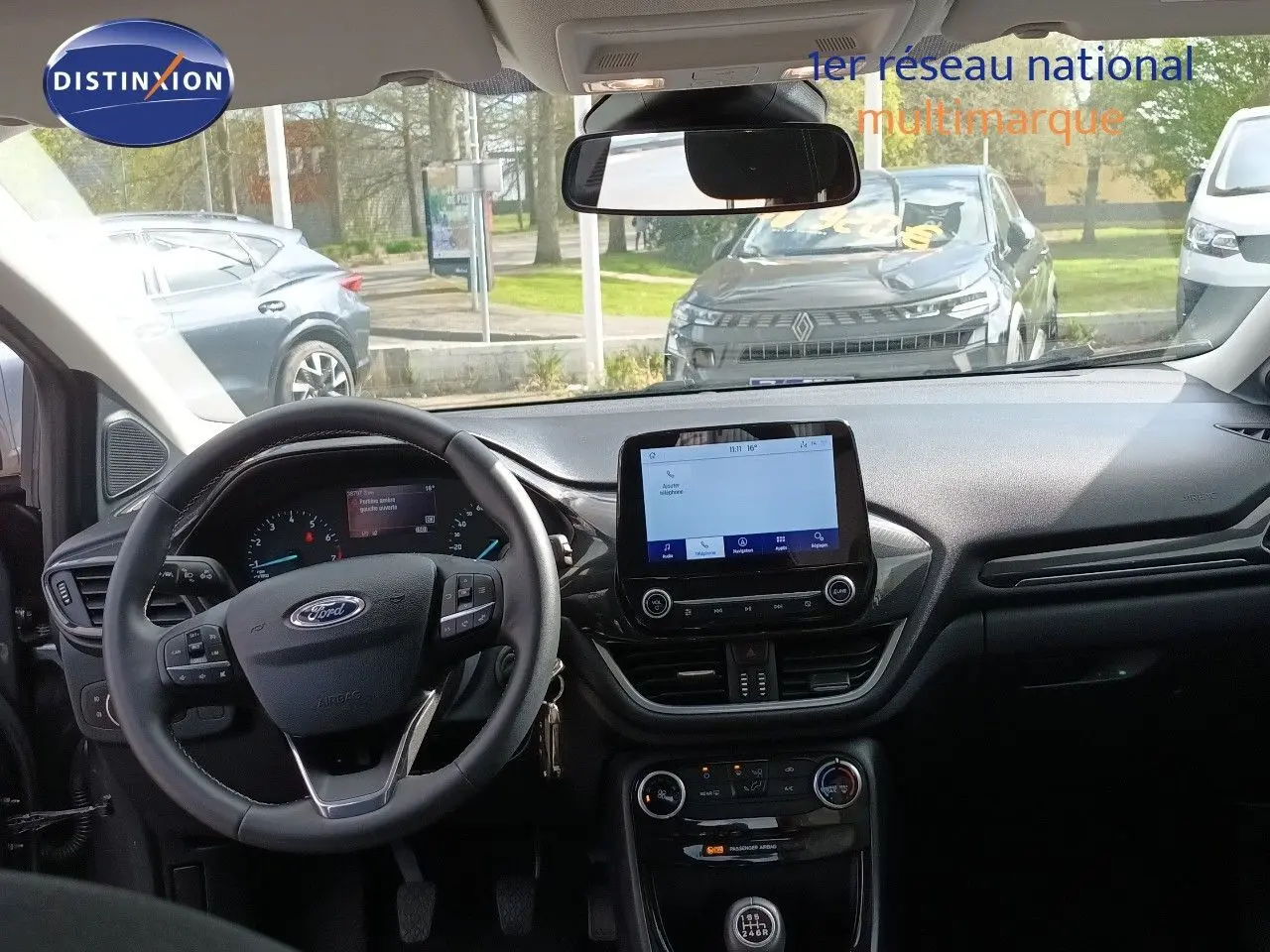 Vue intérieure frontale du tableau de bord et volant noir du Ford Puma gris foncé 2023 avec écran tactile central et boîte manuelle.