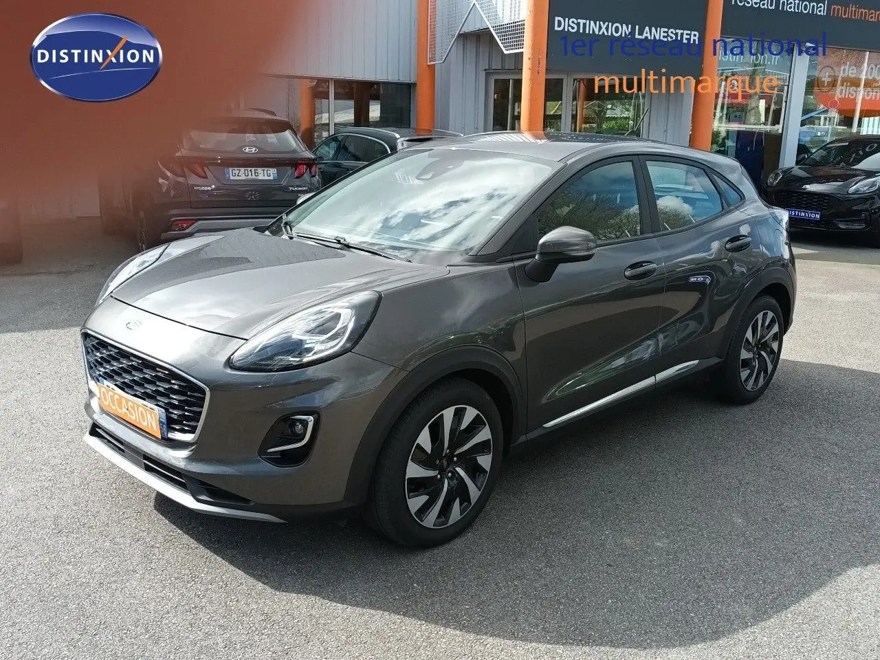Ford Puma gris foncé métal en vue 3/4 avant droit, avec jantes alliage et calandre distinctive Titanium.