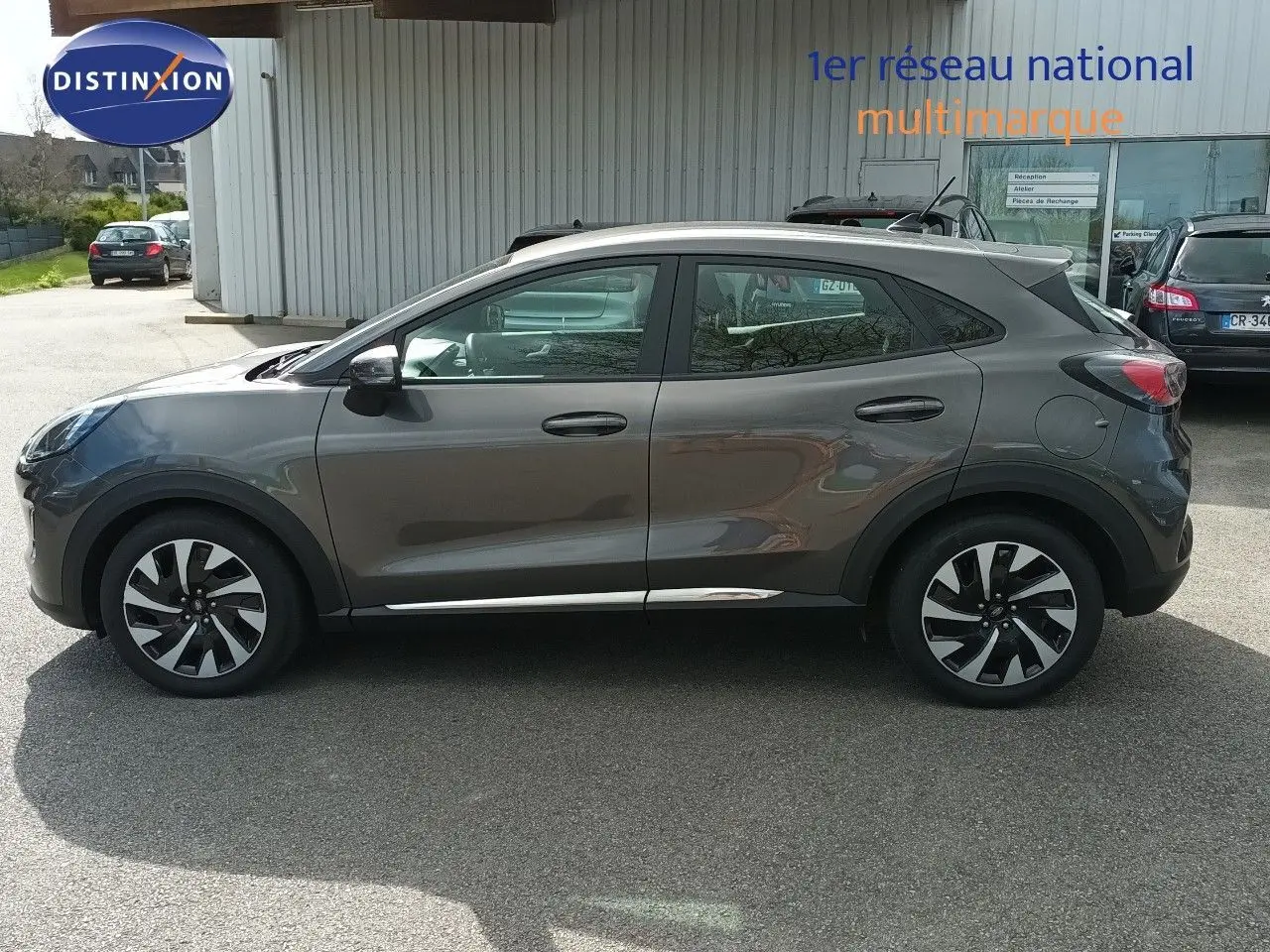 Vue latérale droite d'un Ford Puma gris foncé métallisé, soulignant ses jantes bicolores et sa silhouette compacte.