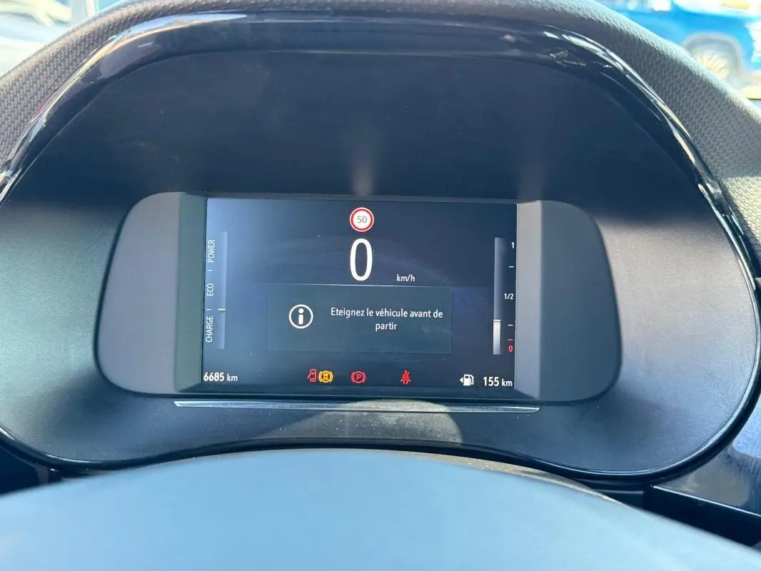 Gros plan sur le tableau de bord numérique de l’Opel Corsa rouge, affichant la vitesse à 0 km/h et divers indicateurs.