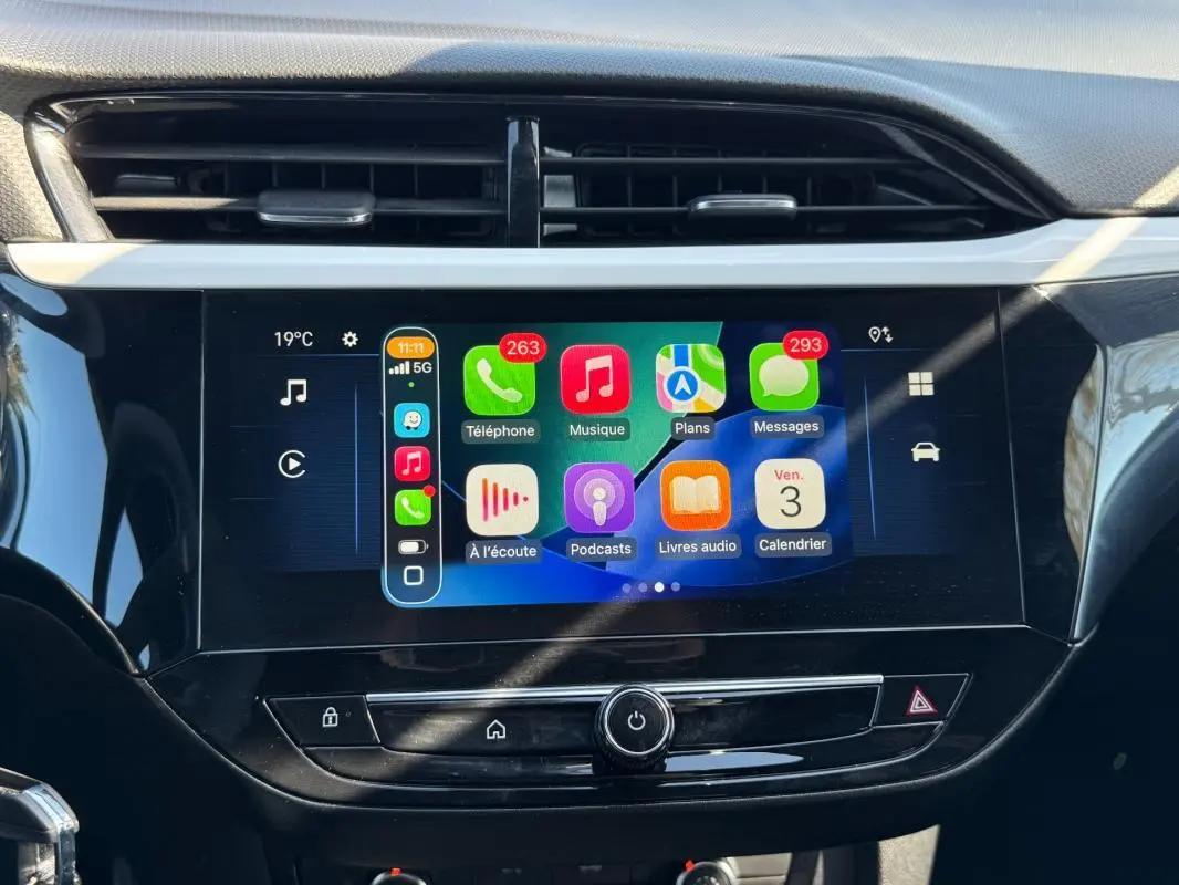 Écran tactile central de l’Opel Corsa rouge 2025 affichant Apple CarPlay avec icônes colorées, vue frontale rapprochée.