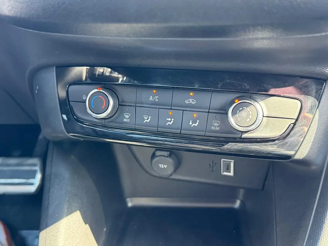 Gros plan sur la console centrale de la climatisation manuelle de l’Opel Corsa 2025, avec boutons et ports USB visibles.