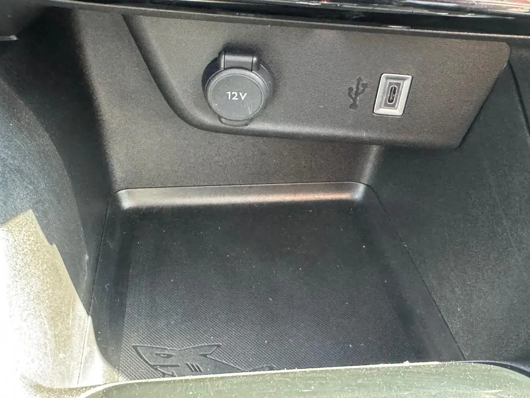 Gros plan sur la prise 12V et port USB-C dans le compartiment de rangement intérieur de l’Opel Corsa rouge.