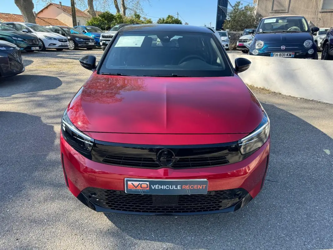 Opel Corsa rouge vue de face, mettant en valeur sa calandre noire brillante et ses phares fins modernes.