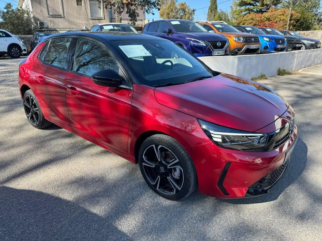 Opel Corsa rouge vue 3/4 avant droit, jantes alliage noires 17 pouces, calandre moderne et phares LED fins.