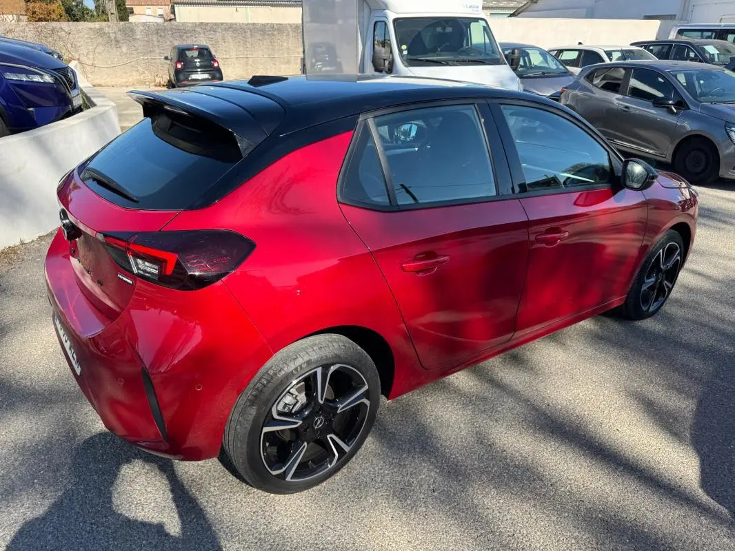 Vue 3/4 arrière droite d'une Opel Corsa rouge 2025 avec toit noir, jantes alliage 17 pouces et feux arrière LED.
