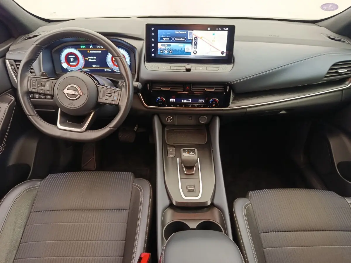 Vue intérieure avant du Nissan Qashqai Tekna 2023 noir, tableau de bord avec écran tactile 12,3 pouces et volant cuir multifonctions.
